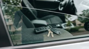 Llaves de coche con mando a distancia y llavero olvidadas en el interior del vehículo, vistas a través de la ventanilla de la puerta cerrada.